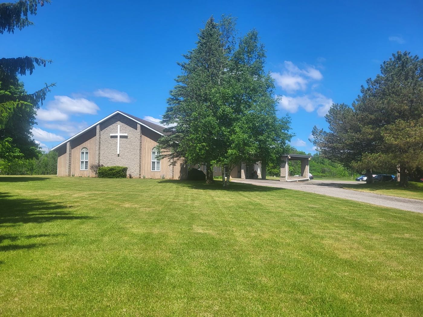 The Flamborough Christian Fellowship church building in Millgrove, Ontario, with its cross, mature trees and green lawn
