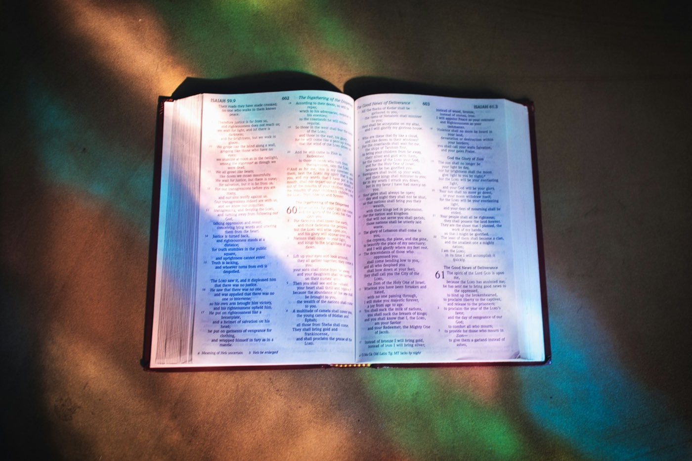 An open Bible lit by warm, stained-glass light